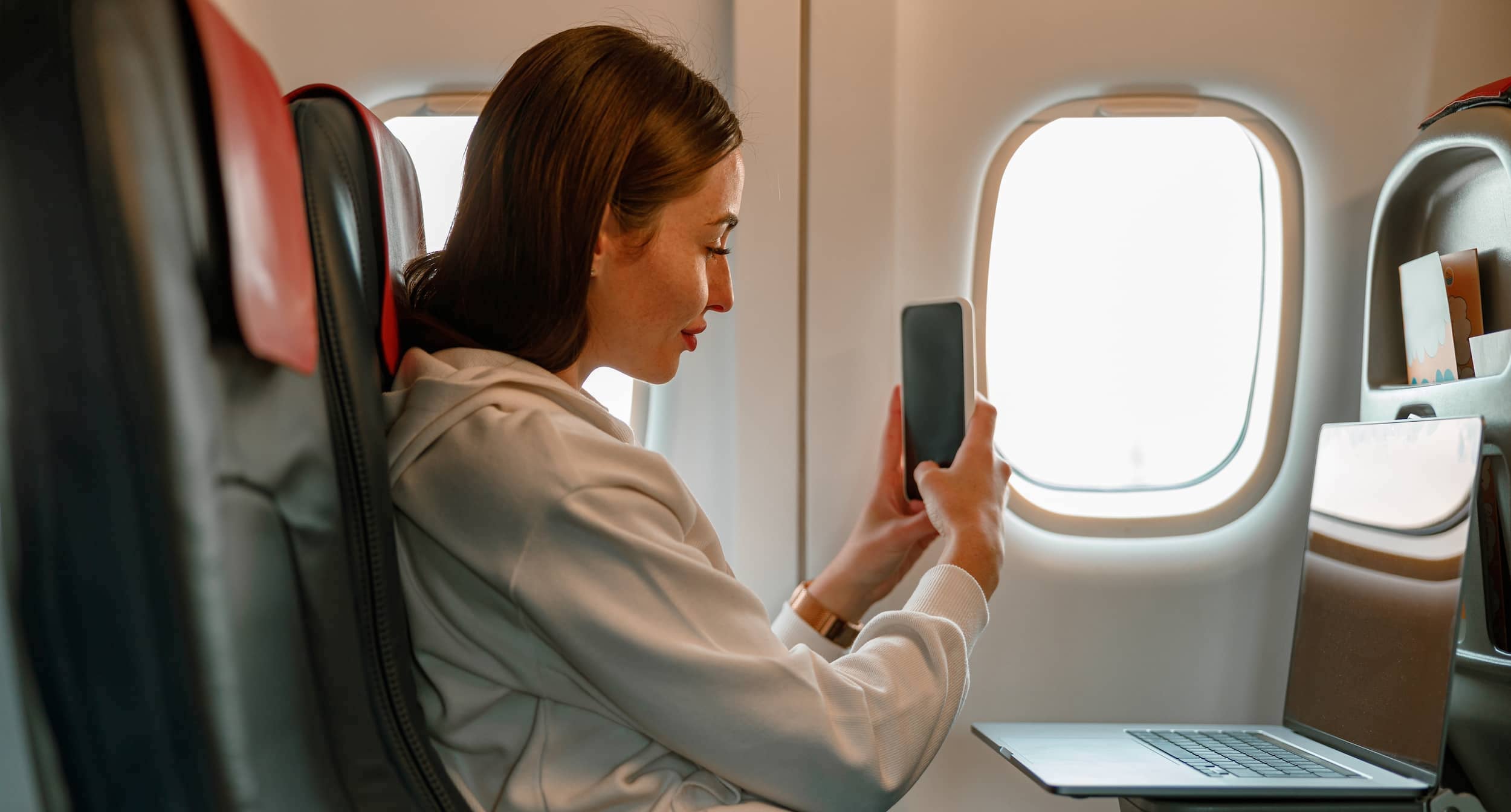 Woman using a cool iPhone accessory on a plane.