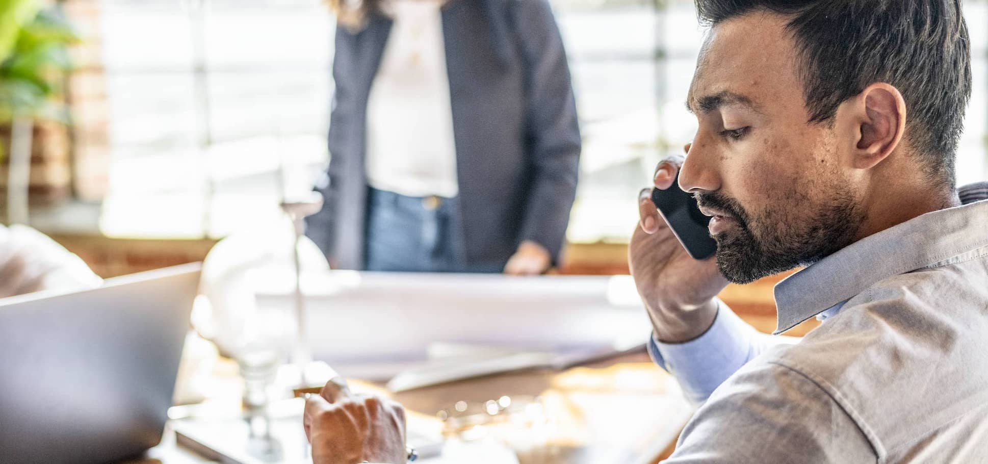 Businessman using Samsung smartphone while looking at smart watch.
